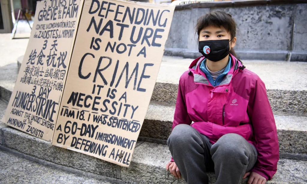 A girl in a pink windbreaker sits on steps.