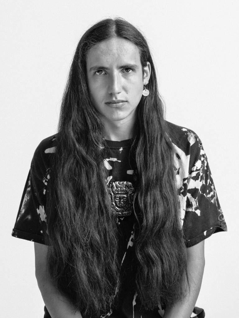 black and white photo of youth with long dark hair. 