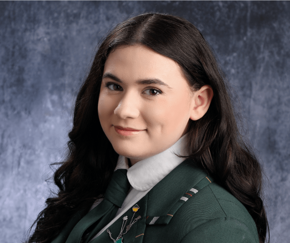 a young person with long brown hair smiles at the camera