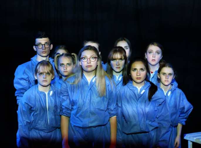 [ID: Eleven youth in matching blue hoodies and sweat pants stare straight ahead. ]
